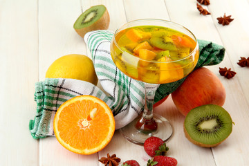 punch in glass with fruits, on white wooden table