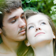 Young happy couple embracing tenderly among green leaves