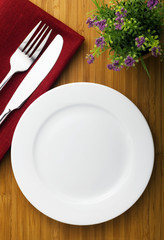 white plate, knife and fork on wood table