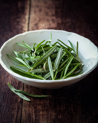 Fresh rosemary leaves in white bowl