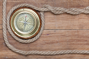 Fototapeta na wymiar Old brass compass and rope on wood