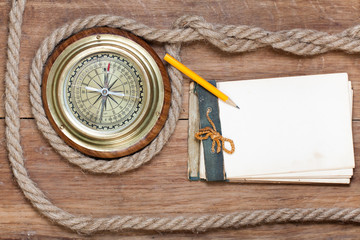 Compass, old notebook, pencil, rope on wood