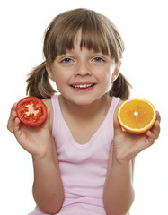 little girl holding a half tomato and a half orange