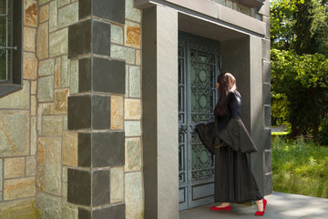 Eine schwarz gekleidete Frau steht vor einem Mausoleum
