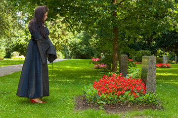 Eine schwarz gekleidete Frau betrachtet eine Gedenkstätte auf e