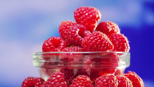 Raspberry fruit heap rotating on blue sky background