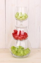 Color candies in glasses on wooden background