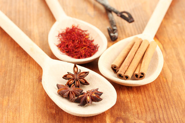 Fragrant spices in wooden spoons on a wooden background