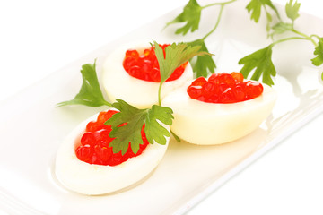 Red caviar in eggs on white plate isolated on white