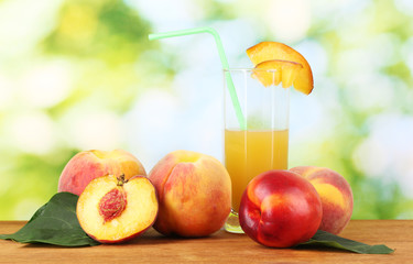 Ripe peaches and juice on wooden table on natural background