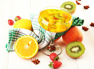 punch in glass with fruits, on white wooden table