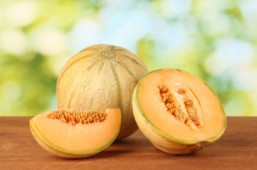 Cut melon on wooden table on green background