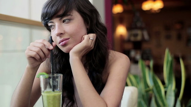 Young beautiful pensive woman drinking cocktail in cafe