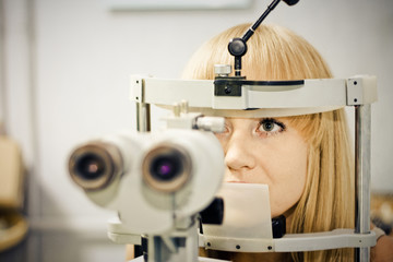 woman having her eyes on a slit lamp