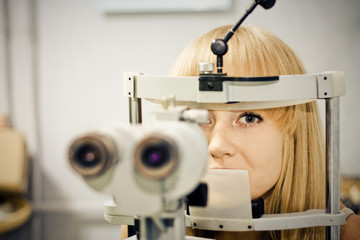 woman having her eyes on a slit lamp