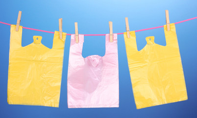 Cellophane bags hanging on rope on blue background