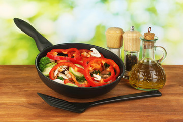 frying pan with vegetables on green background