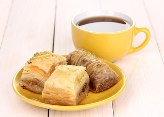 Sweet baklava on plate with tea on wooden background