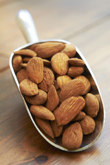 Scoop Of Almonds On Wooden Surface
