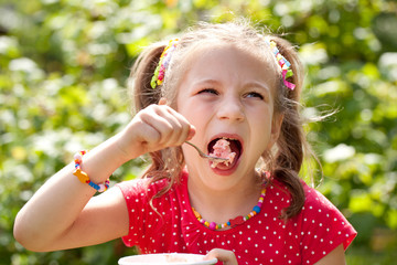 Girl with pigtails eats with relish ice cream