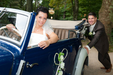 bräutigam schiebt das hochzeitsauto an