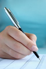 woman's hand writing entries in a notebook