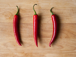 Three red chilli peppers on wood