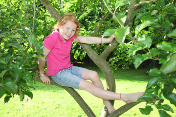 Fröhliches Mädchen sitzt in einem Baum