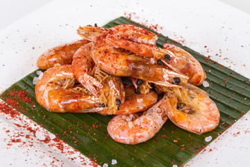 fried black tiger prawns with herbs and spices on banana leaf