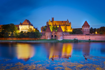 Malbork castle in Poland at night with reflection in Nogat river