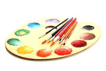 wooden art palette with paint and brushes isolated on white