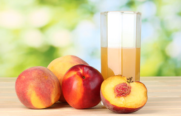 Ripe peaches and juice on wooden table on natural background