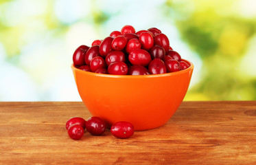fresh cornel berries in orange bowl on green background