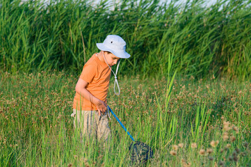 Little child hunting for butterfly by the lake