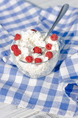 Домашний творог и малина в стеклянной чашке и ложка на салфетке
