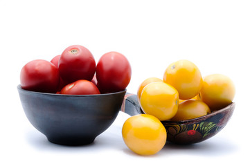 Tomatoes in a bowl, parsley, wooden spoon, yellow tomato