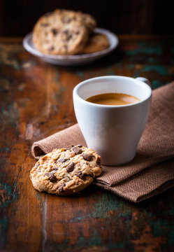Cup of espresso and chocolate chip cookies on wooden table