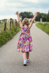 Walking toddler with her hands up in the air