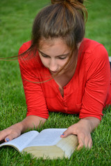 Dziewczyna czyta książkę na łące - obrazy, fototapety, plakaty