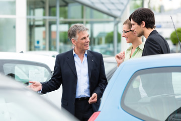 Autohändler und Kunden schauen ein Auto an