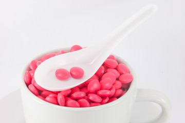 closed-up pink color pills in spoon and a cup