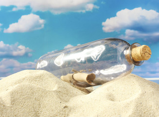 Fototapeta na wymiar Butelka szklana z uwagą wewnątrz na piasku, na tle niebieskiego nieba