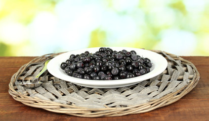 Fresh blueberries in plate on green background