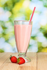 Strawberry milk shake on wooden table on bright background