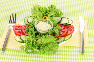 Chopped vegetables and sauce on plate on green tablecloth