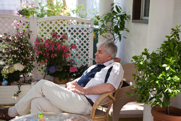 Attractive man fifty with grey hairs sitting on patio