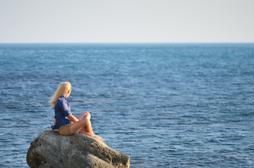 Girl in the blue shirt looks at the sea
