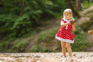 Naklejka premium Adorable girl throw stone to river stream in park