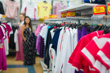 Variety of t-shirts and sweaters on stands in supermarket