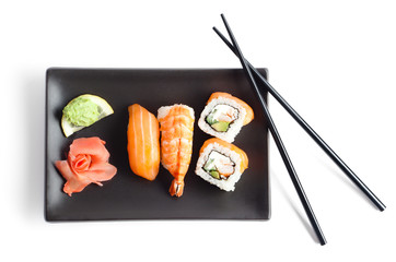 Black plate with sushi and chopsticks, isolated